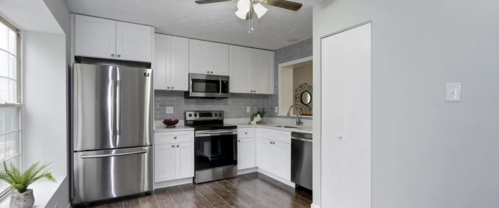 Modern kitchen with white cabinets, stainless steel appliances, and gray subway tile backsplash.