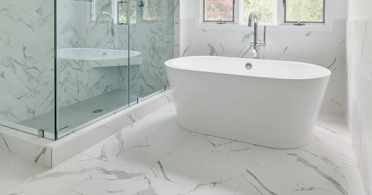 White bathroom with white freestanding tub, white marble floor, and white walk-in shower with glass doors
