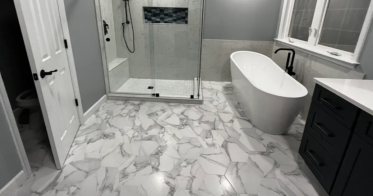 Closeup of hexagon mosaic style bathroom with freestanding tup and walk-in shower with shower niche