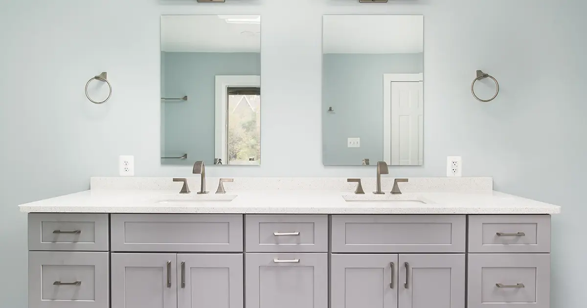Light gray bathroom cabinets with shaker style doors and large double sinks with double mirrors