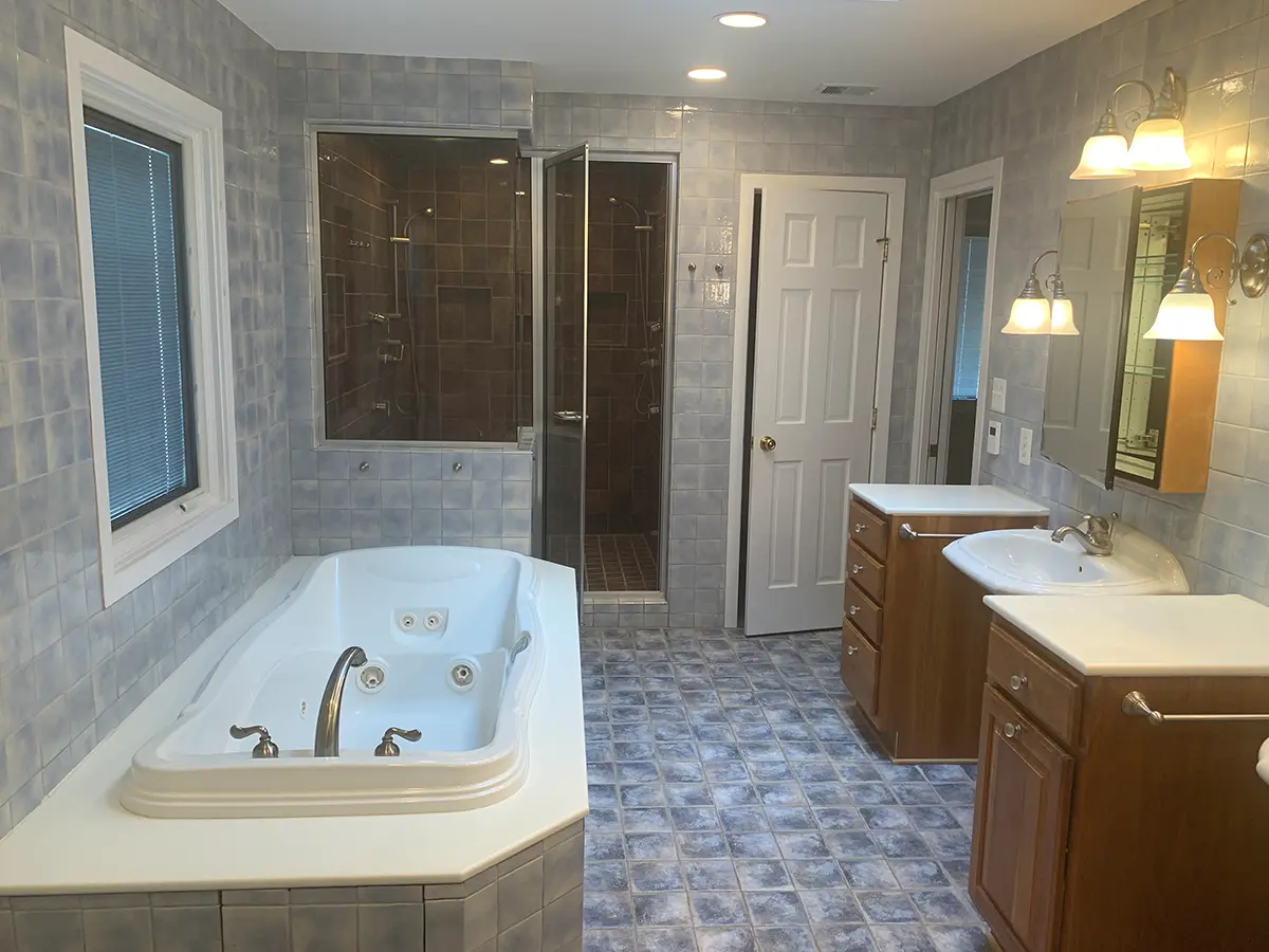 Older bathroom with brown cabinets and gray tile