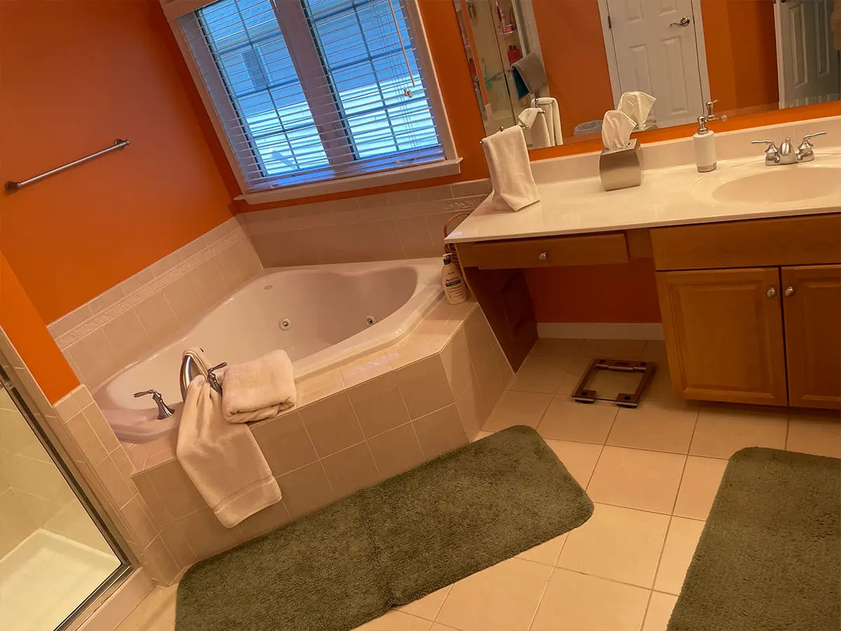 Outdated orange bathroom with corner tub and brown wooden cabinets before bathroom remodel from Gigi Homes and Construction