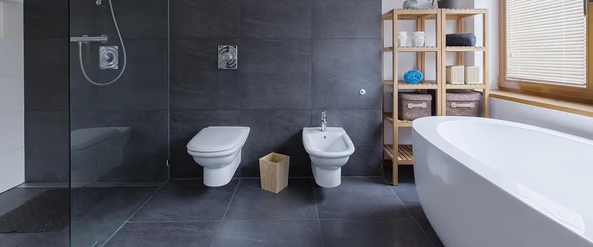 A bathroom remodel with large black tile floor and walls