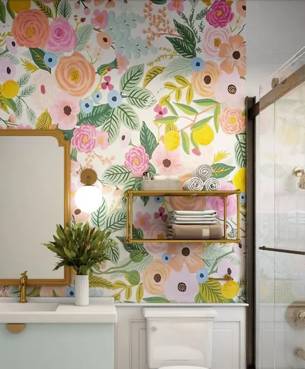 Vibrant bathroom with a floral wallpaper, brass fixtures, a modern vanity, and neatly arranged towels on a stylish shelf