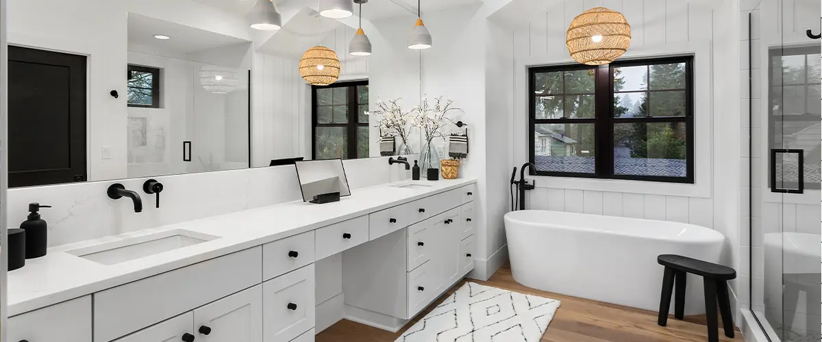 Beautiful bathroom in luxury home with double vanity, bathtub, mirror, sinks, shower, and hardwood floor