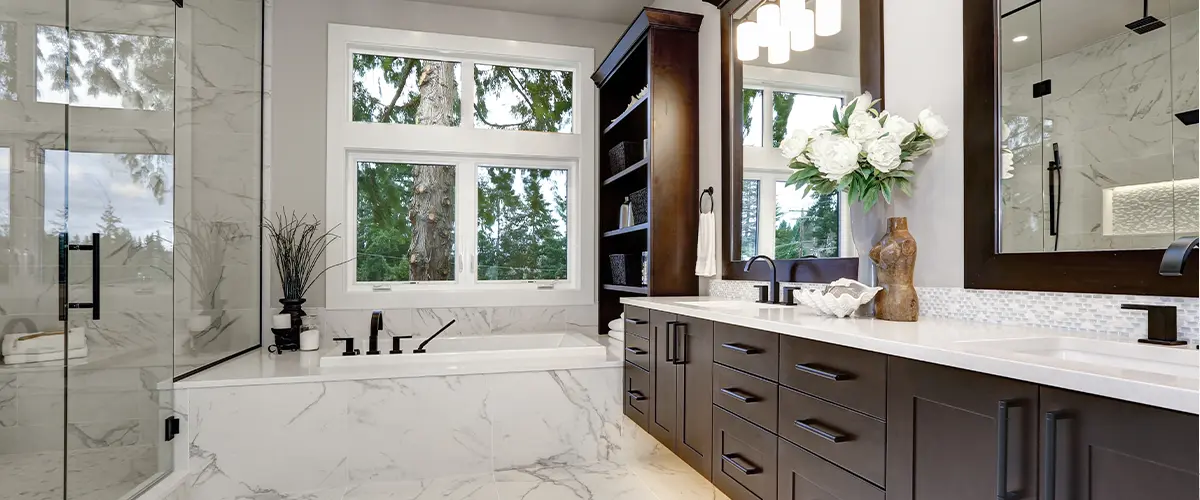 Master modern bathroom interior in luxury home with dark hardwood cabinets, white tub and glass door shower