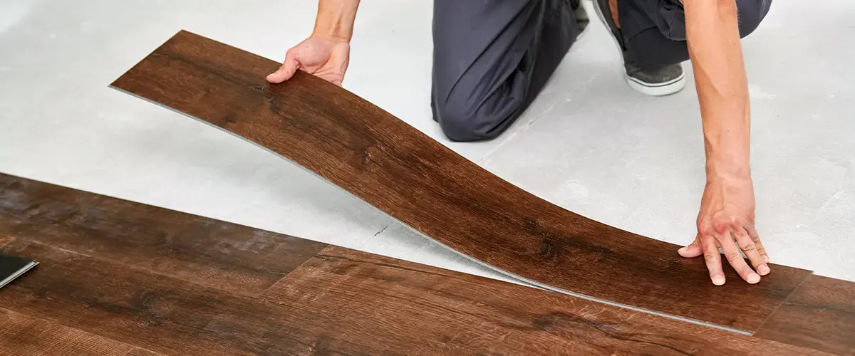 Installing vinyl plank flooring, close-up of hands placing wood-look vinyl planks, highlighting Porcelain Tile vs. Vinyl Plank The Ultimate Flooring Showdown