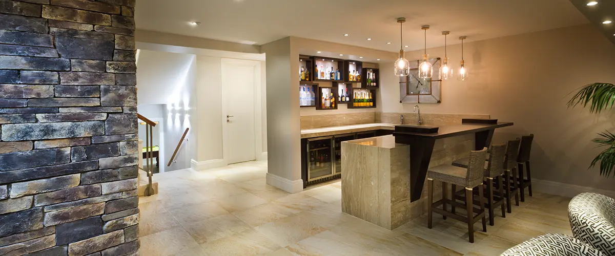 Modern basement bar with stone wall and elegant pendant lighting.