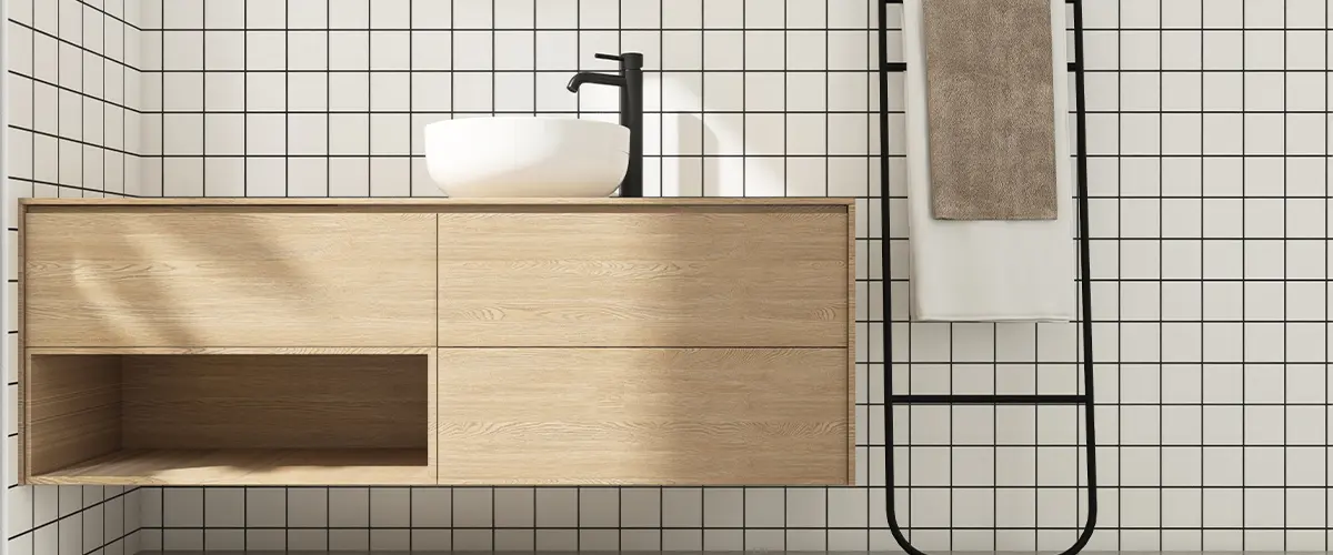 Wooden brown bathroom vanity counter, white washbasin, black faucet, mirror in sunlight on square white tile black grout