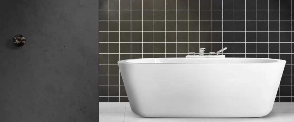 A modern, high-contrast bathroom with a freestanding white tub set against a wall featuring matte black square tiles with white grout lines.