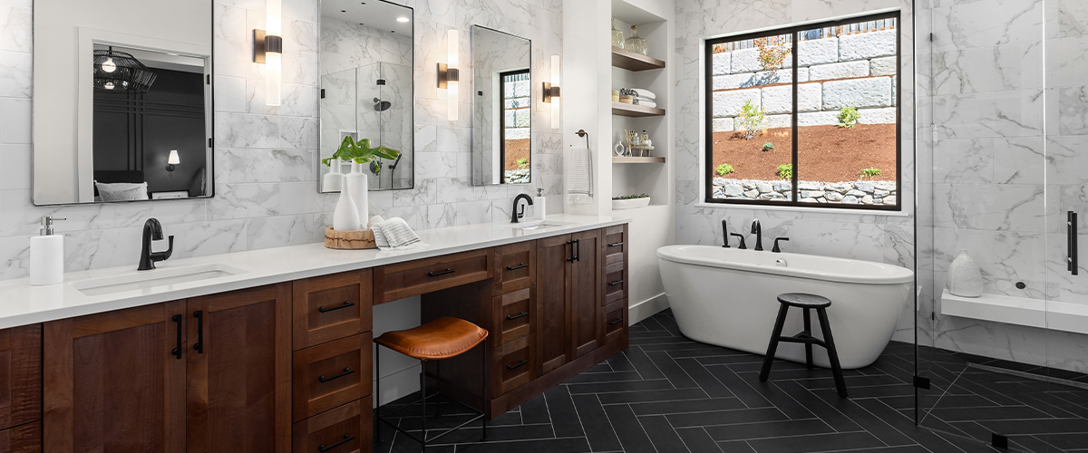 Luxurious bathroom with white marble walls, dark wood cabinets, double vanity, freestanding tub, and large window.