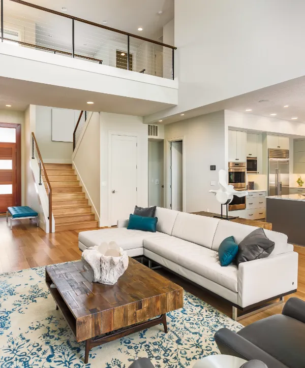 a modern living room featuring a light-colored sectional sofa, a rustic wooden coffee table, and a blue and white area rug