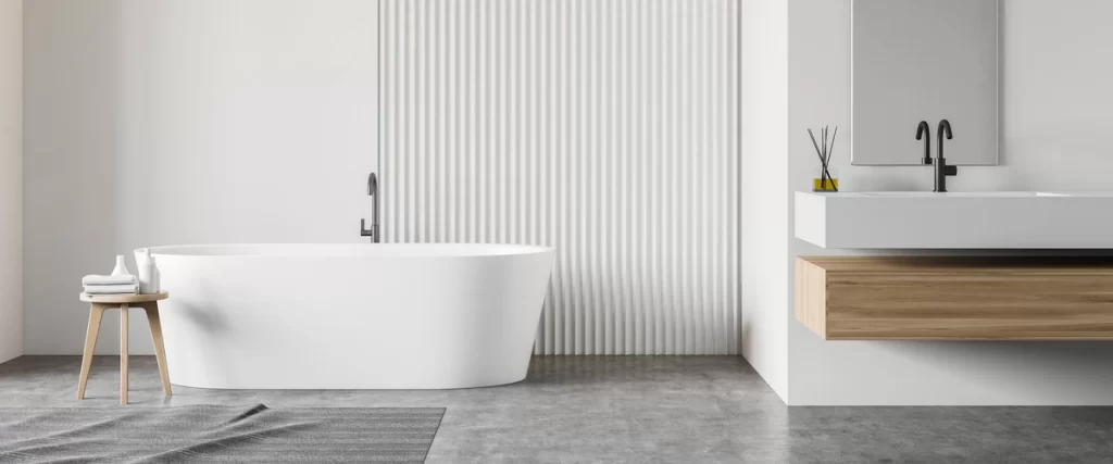 Minimalist spa-style bathroom featuring a white freestanding oval bathtub against a textured wall with a floating wooden vanity and concrete floors.