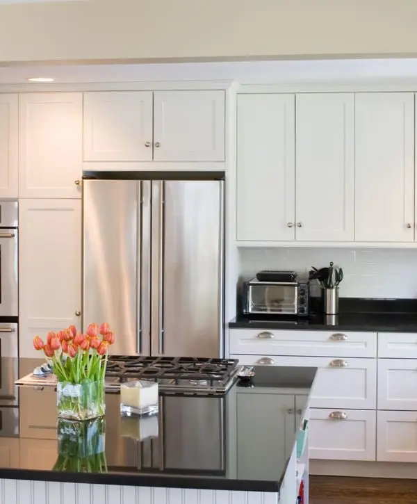 Professional kitchen remodeling in Fairfax Station, VA featuring a sleek black granite island with an integrated gas cooktop, white shaker cabinets, and stainless steel appliances.
