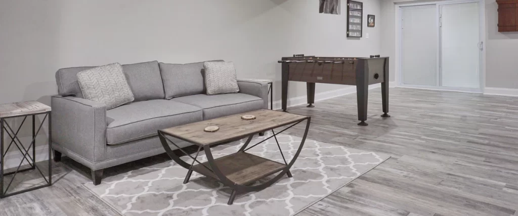 A luxury basement entertainment level featuring a professional pool table, custom wood bar, and elegant tile flooring.