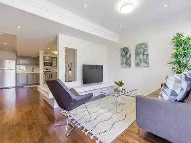 basement remodeling, open space living room and kitchen with hardwood floor, sofa and tv, modern kitchen appliances